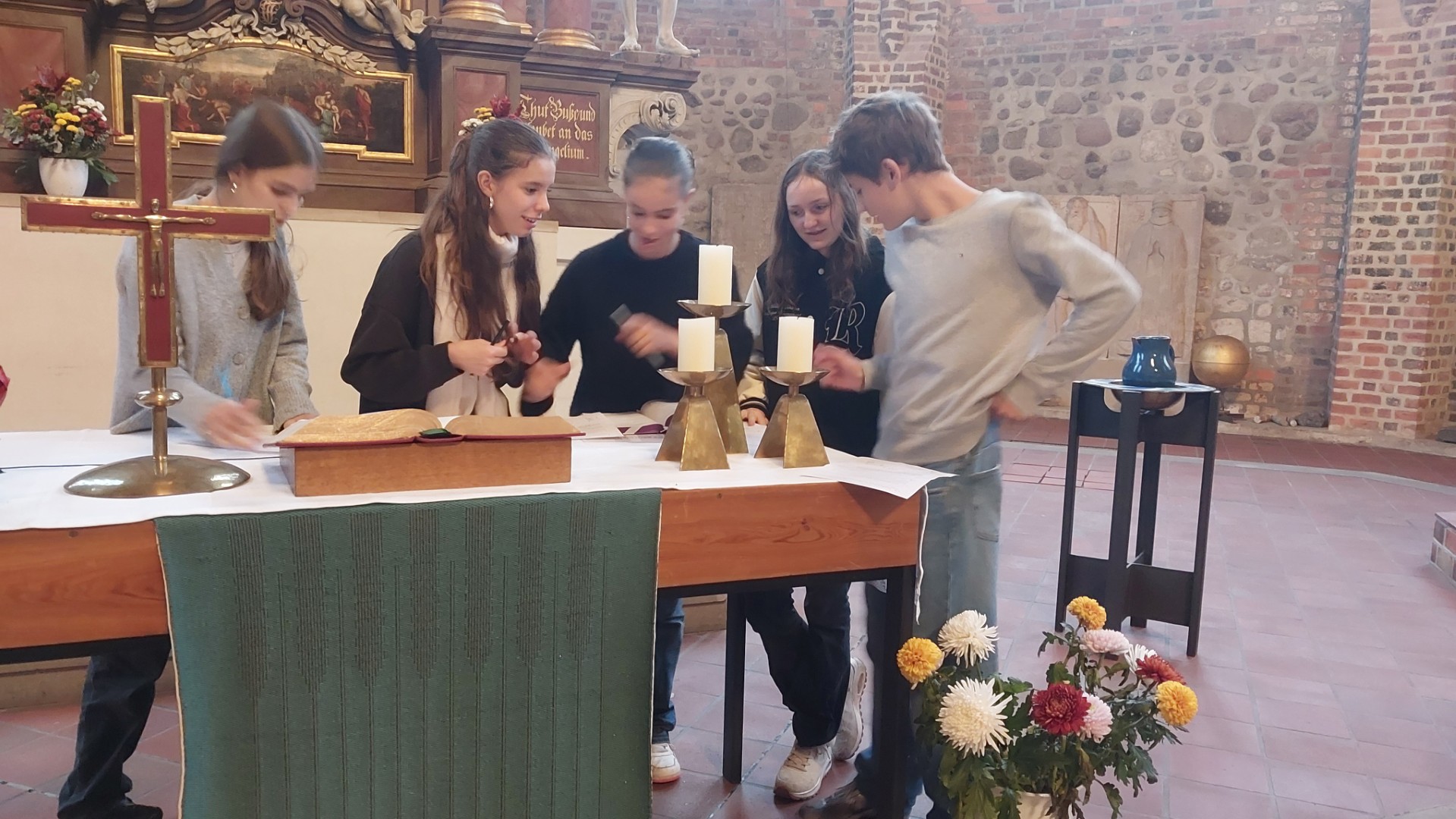 Vier Jugendliche beugen sich über einen Altar und machen Notizen